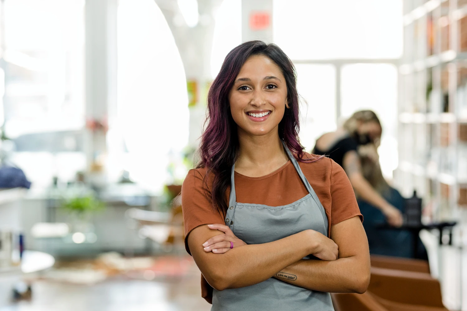 Jovem empreendedor, de camisa marrom, sorri em frente ao seu negócio, simbolizando o sucesso ao entender como abrir empresa Simples Nacional e gerenciar seu próprio empreendimento.